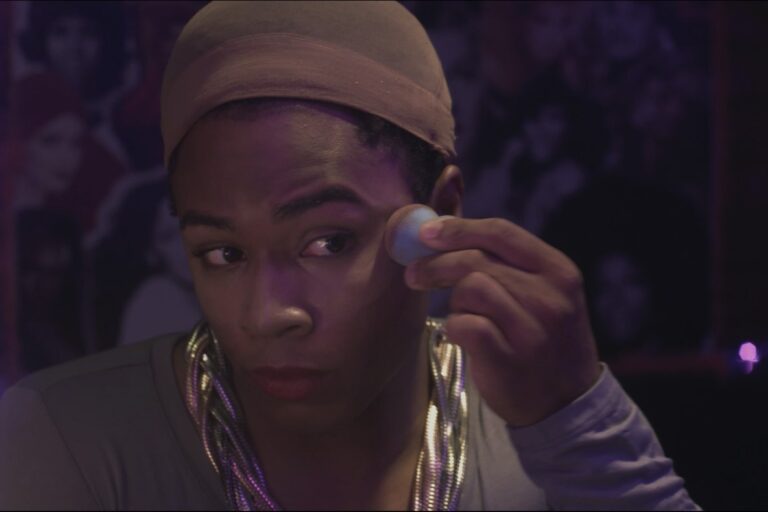 O diretor Pedro Jorge orientando uma cena que mistura elementos de um ringue de boxe com iluminação de palco de performance drag.