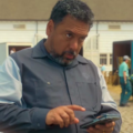 O ator Felix Solis caracterizado como seu personagem em uma cena de série, segurando um smartphone.