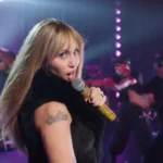Miley Cyrus usando a icônica peruca loira de Hannah Montana no palco do especial de 20 anos.