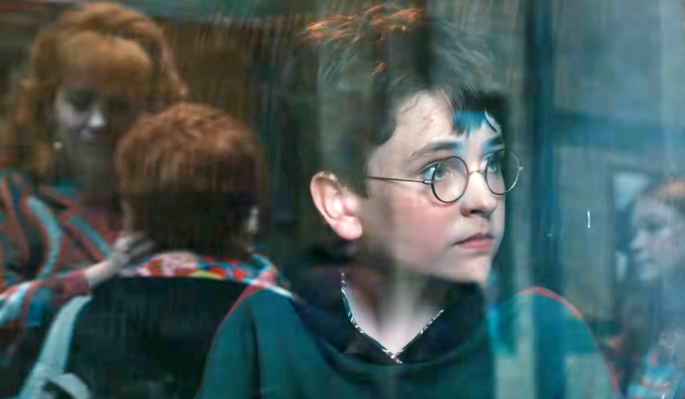 Harry Potter olhando para rua de dentro de um trem.