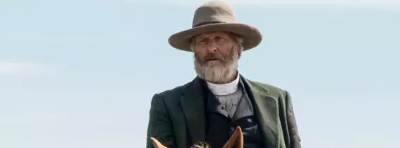 O ator Jeff Daniels sorrindo em um evento de tapete vermelho, vestindo um terno escuro.