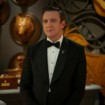 O apresentador Peter Serafinowicz em cenário do reality show Million Dollar Secret da Netflix.