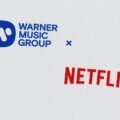 Logotipos da Netflix e Warner Music Group sobre fundo tecnológico