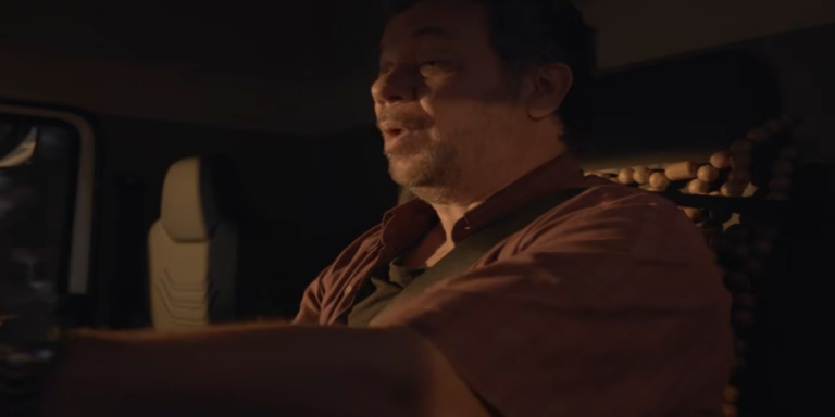 O ator Márcio Vito interpretando o homem pendurado na frente de um caminhão em cena do filme Eu Não Te Ouço.