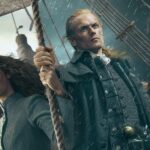 O ator César Domboy sorridente durante entrevista de divulgação da série Outlander.