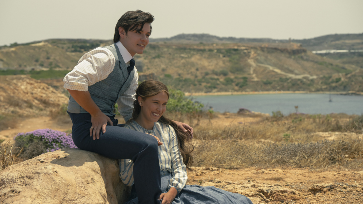 Millie Bobby Brown como Enola Holmes em cena do terceiro filme com figurino de época e ambientação europeia