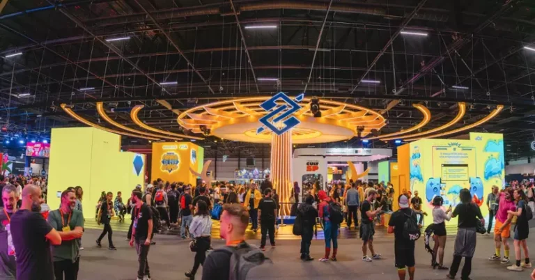 Público reunido em frente ao palco principal da gamescom latam com luzes coloridas e telões ao fundo.