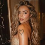 Karol G durante apresentação em palco de festival com iluminação intensa e público ao fundo