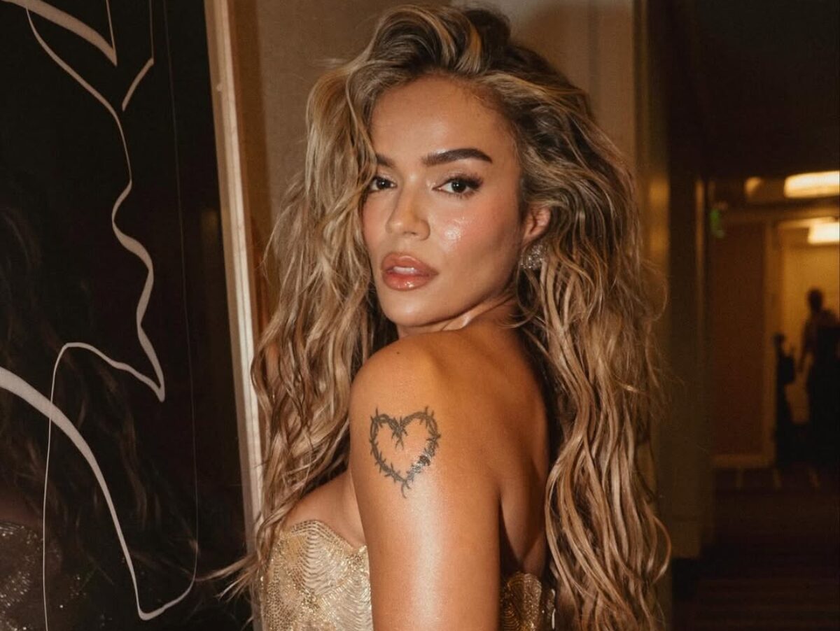 Karol G durante apresentação em palco de festival com iluminação intensa e público ao fundo