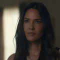 Olivia Munn em entrevista durante programa de TV, relatando bastidores de gravação com colega de elenco em cena de ação.