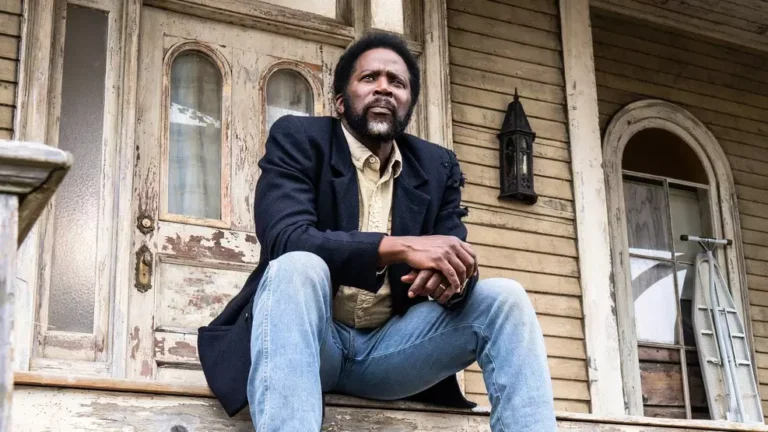 Cena sombria de Origem mostra personagem em cidade misteriosa cercada por floresta