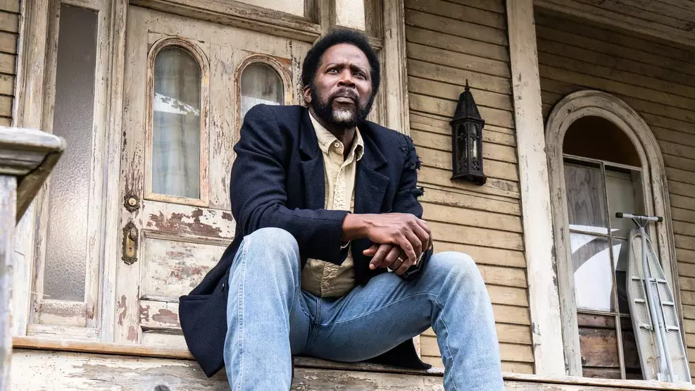 Cena sombria de Origem mostra personagem em cidade misteriosa cercada por floresta