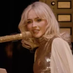 Sabrina Carpenter sentada ao piano durante sua apresentação no festival Coachella.
