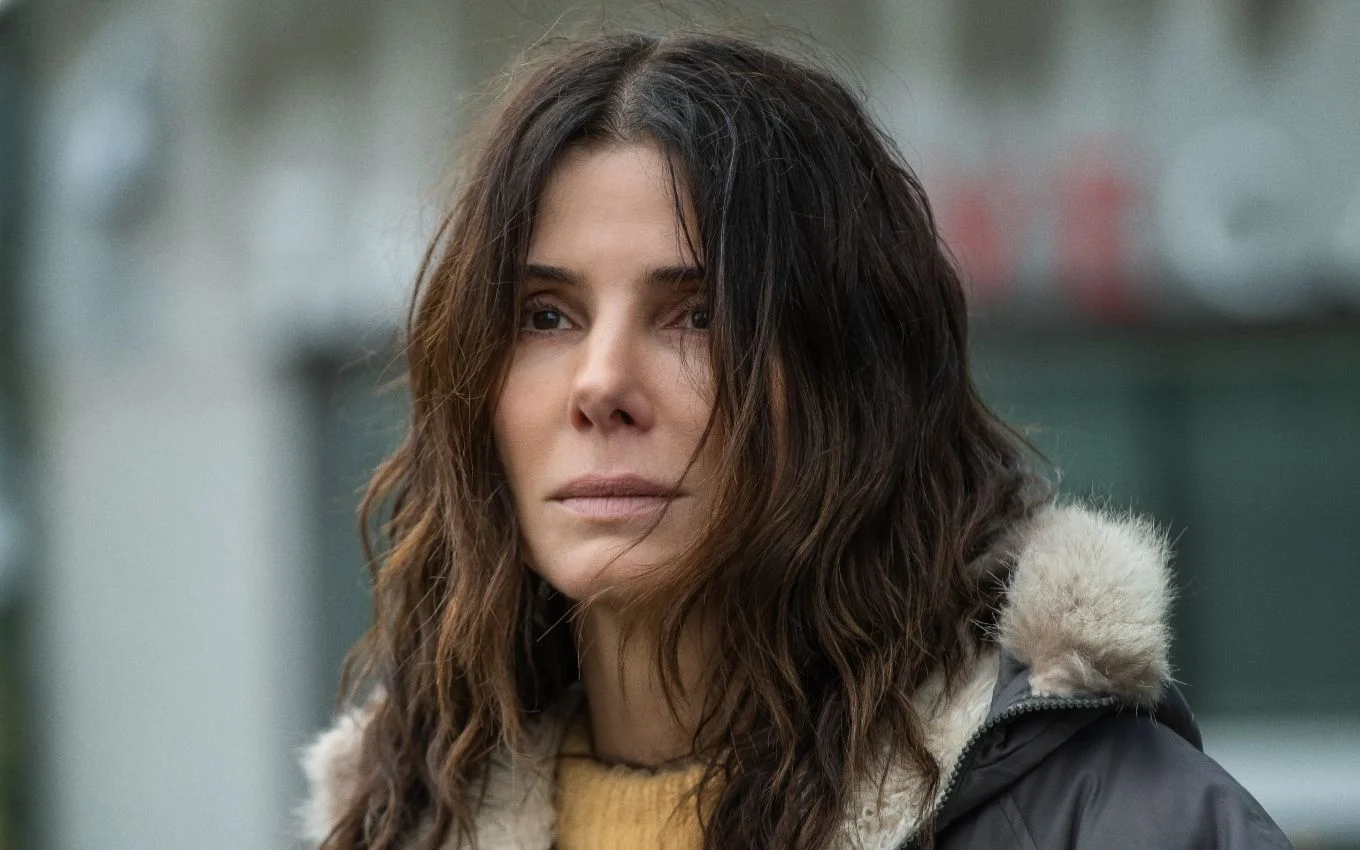 Sandra Bullock sorrindo em evento de divulgação do filme Da Magia à Sedução 2, vestindo blazer escuro e camisa branca.