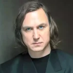 Foto de Lars Eidinger em estúdio, mostrando o ator sendo maquiado para o papel de Brainiac em Superman 2: Homem do Amanhã