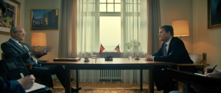 O ator Jeff Daniels caracterizado como o presidente Ronald Reagan em uma sala de reuniões no filme The Brink of War.