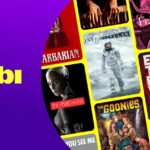 Tela com interface de streaming exibindo catálogo de filmes Tubi com destaque para Jogos Vorazes e Priscilla em seleção de maio