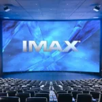 Sala de cinema IMAX com tela grande e projeção de filme em formato premium.