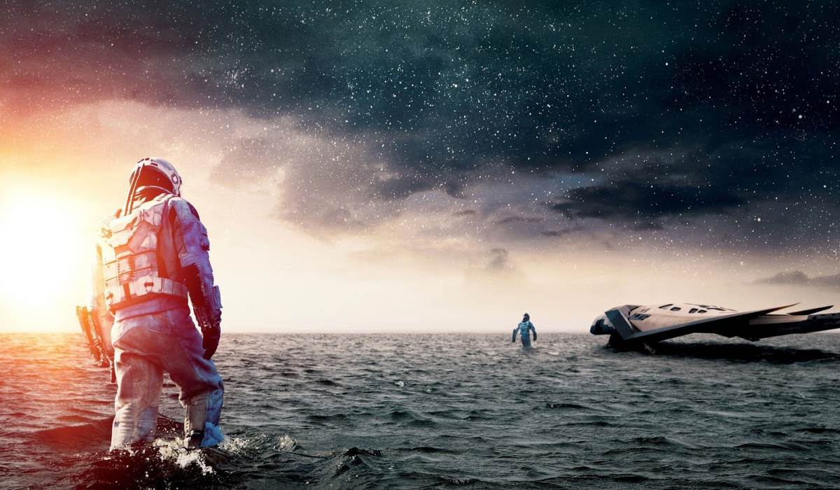 Cena de Interestelar mostrando exploração de planeta com ambiente hostil e céu alienígena