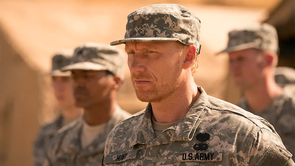 Cena dramática e sombria onde Owen Hunt segura Cristina Yang, retratando o momento crítico de seu episódio de estresse pós-traumático no quarto.
