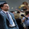 Jordan Belfort (Leonardo DiCaprio) em cena de “O Lobo de Wall Street” durante momento de ascensão em Wall Street, cercado por luxo e excesso financeiro.