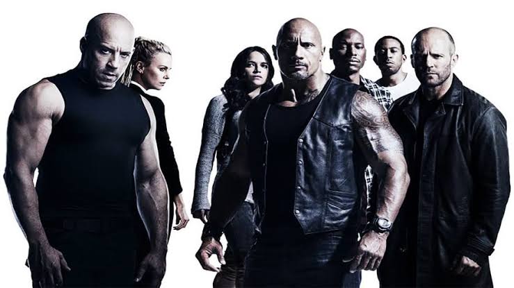 Dominic Toretto aparece ao lado de um carro na franquia Velozes e Furiosos.
