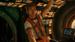 Ryan Gosling como o astronauta Ryland Grace dentro de uma nave espacial tecnológica com iluminação dramática.