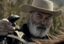 O ator Alec Baldwin caracterizado para o filme Rust: A Lei do Oeste, vestindo trajes de época em um cenário de faroeste.