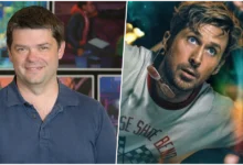 Fotografia em plano médio de Christopher Miller, homem branco de cabelo castanho curto, sorrindo e falando em um microfone em pé em um evento de lançamento de "Devoradores de Estrelas". Ele veste um blazer azul-marinho e uma camisa cinza. O fundo está desfocado, mostrando pessoas e luzes do evento.