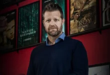 Nicholas Hoult usando uma máscara de lobo em cena de assalto do filme Como Roubar um Banco.