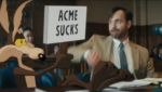 Cena do filme Coyote vs Acme com Wile E Coiote em interação com personagem humano no tribunal
