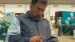O ator Felix Solis caracterizado como seu personagem em uma cena de série, segurando um smartphone.