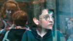 Harry Potter olhando para rua de dentro de um trem.