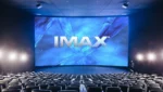 Sala de cinema IMAX com tela grande e projeção de filme em formato premium.