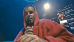 Justin Bieber no palco do Coachella cantando em frente a um notebook em uma estrutura simples.