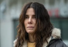 Sandra Bullock sorrindo em evento de divulgação do filme Da Magia à Sedução 2, vestindo blazer escuro e camisa branca.